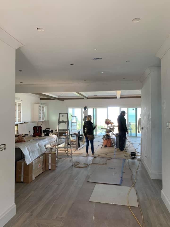 People working in a home under construction, with tools, boxes, and unfinished floors.