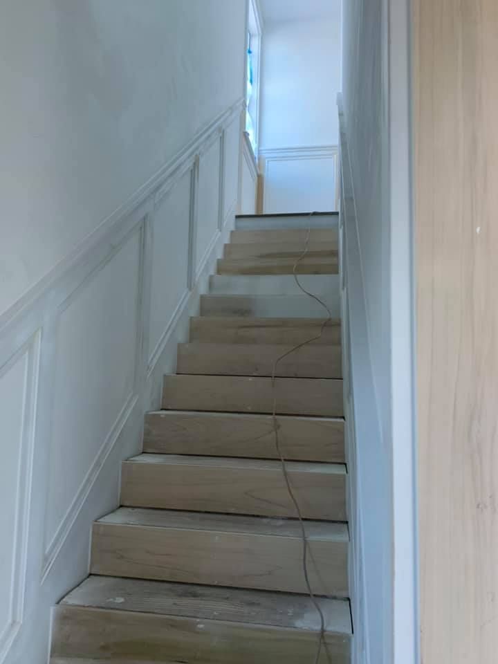 Wooden staircase with white paneling and a window at the top.