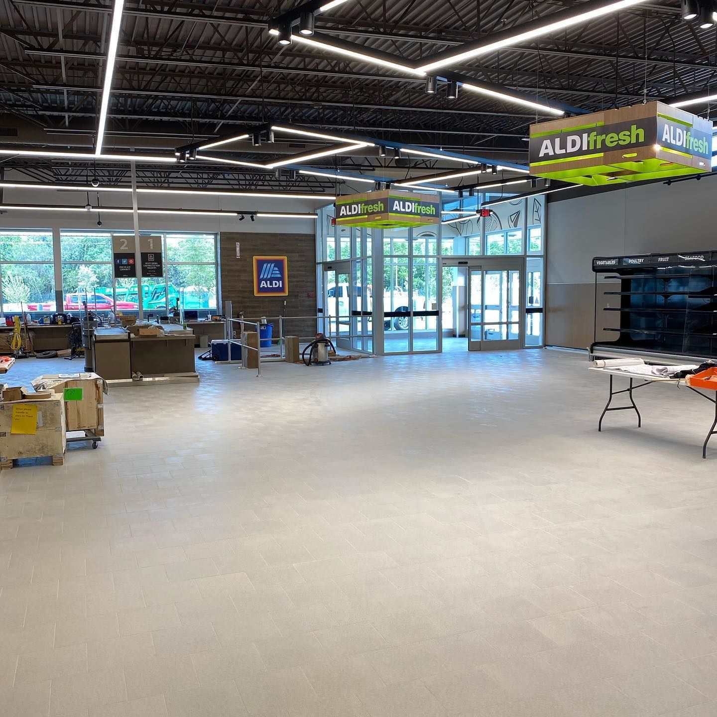 Interior view of an Aldi grocery store under construction. Displays, entrance, and Aldifresh sign are visible.