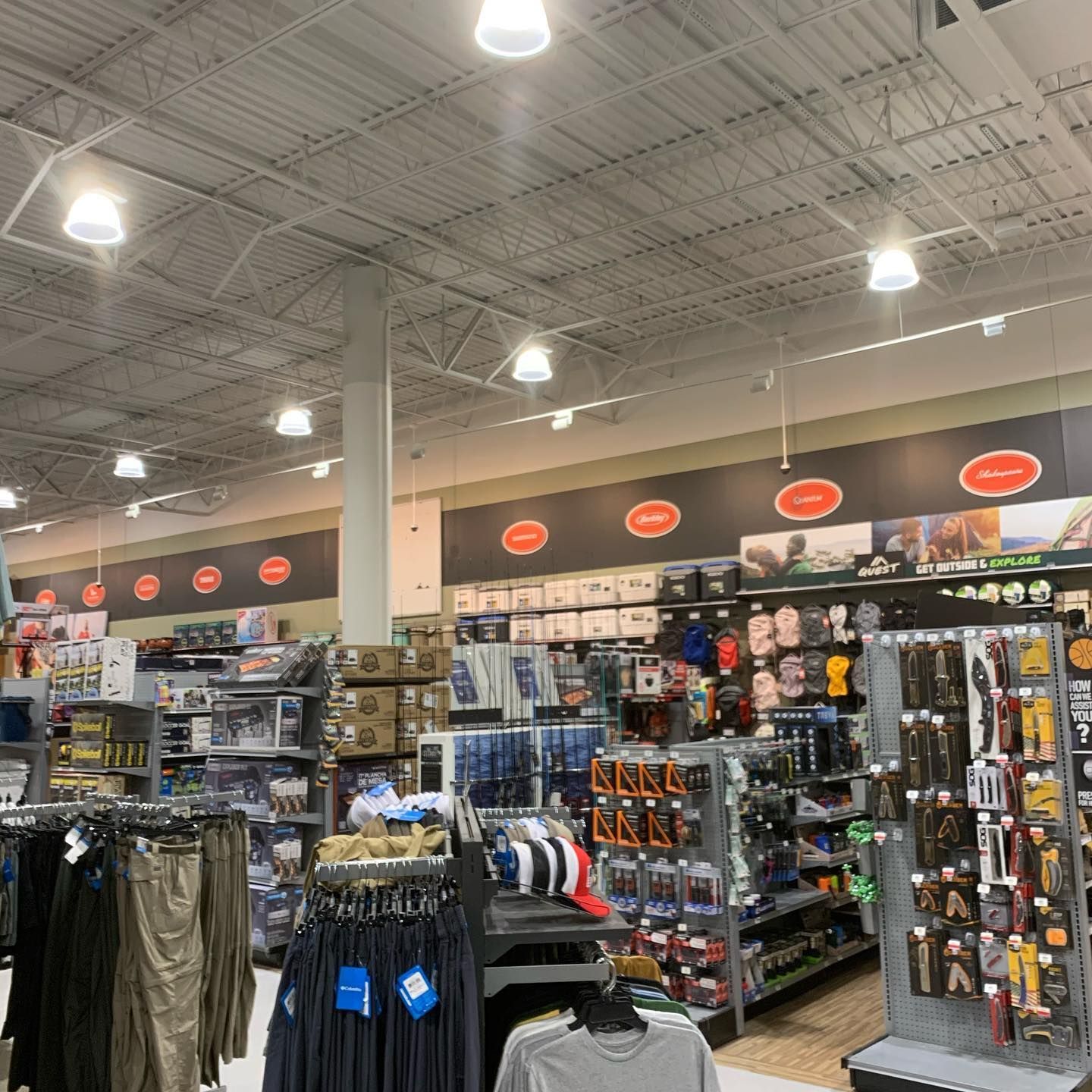 Inside a retail store, goods displayed on shelves, hanging clothes; bright lights illuminate the space.