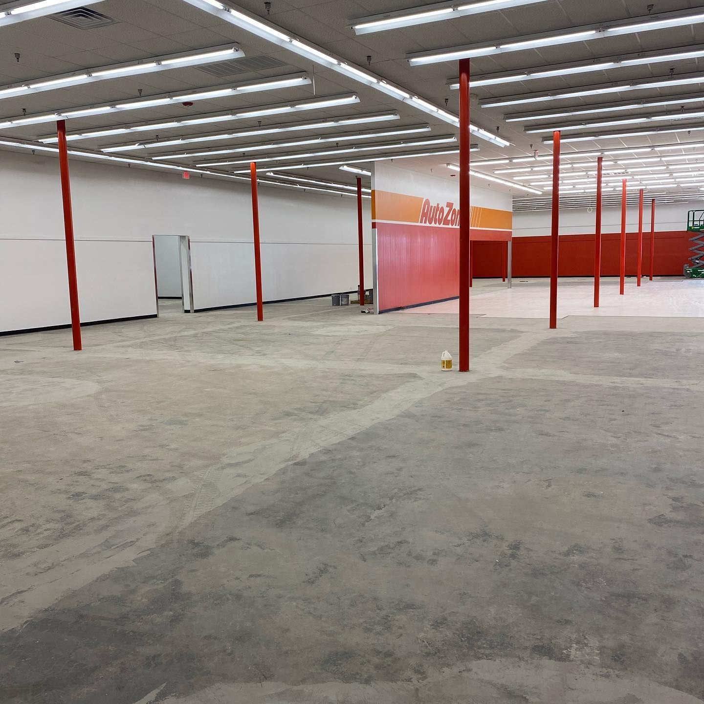 Empty store interior; orange support beams, white walls, concrete floor.