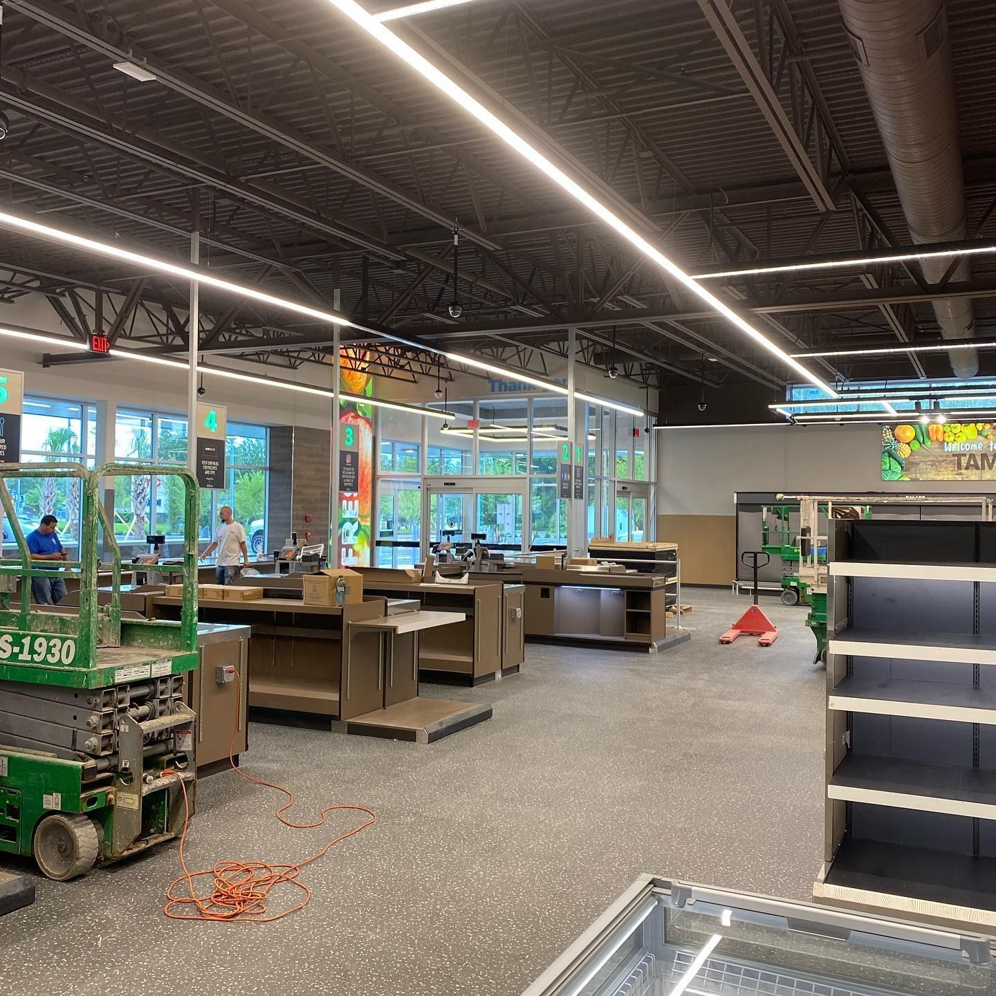 Interior of a grocery store under construction. Checkout counters and empty shelves are visible.