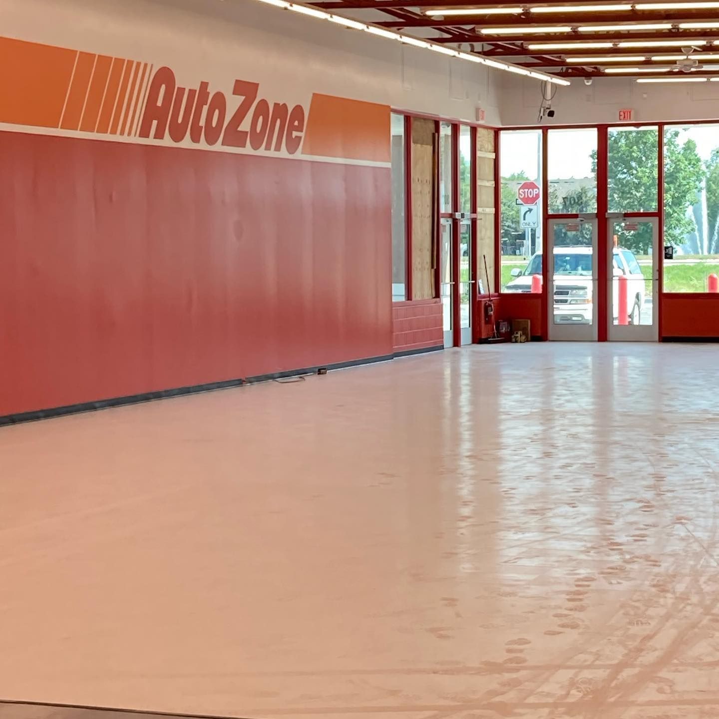 Interior of an empty AutoZone store. Red and orange branding on a red wall, with a glossy floor.