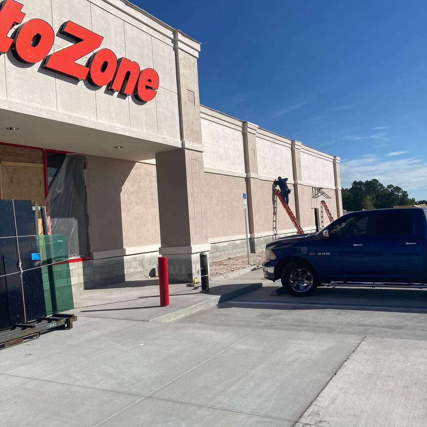 Blue pickup truck parked at AutoZone store entrance; construction work present.