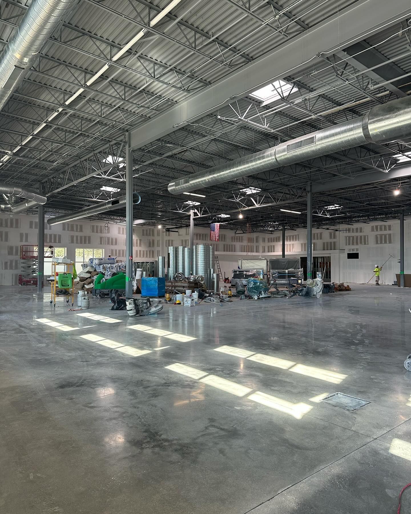 Large, empty warehouse under construction with exposed metal beams and equipment.