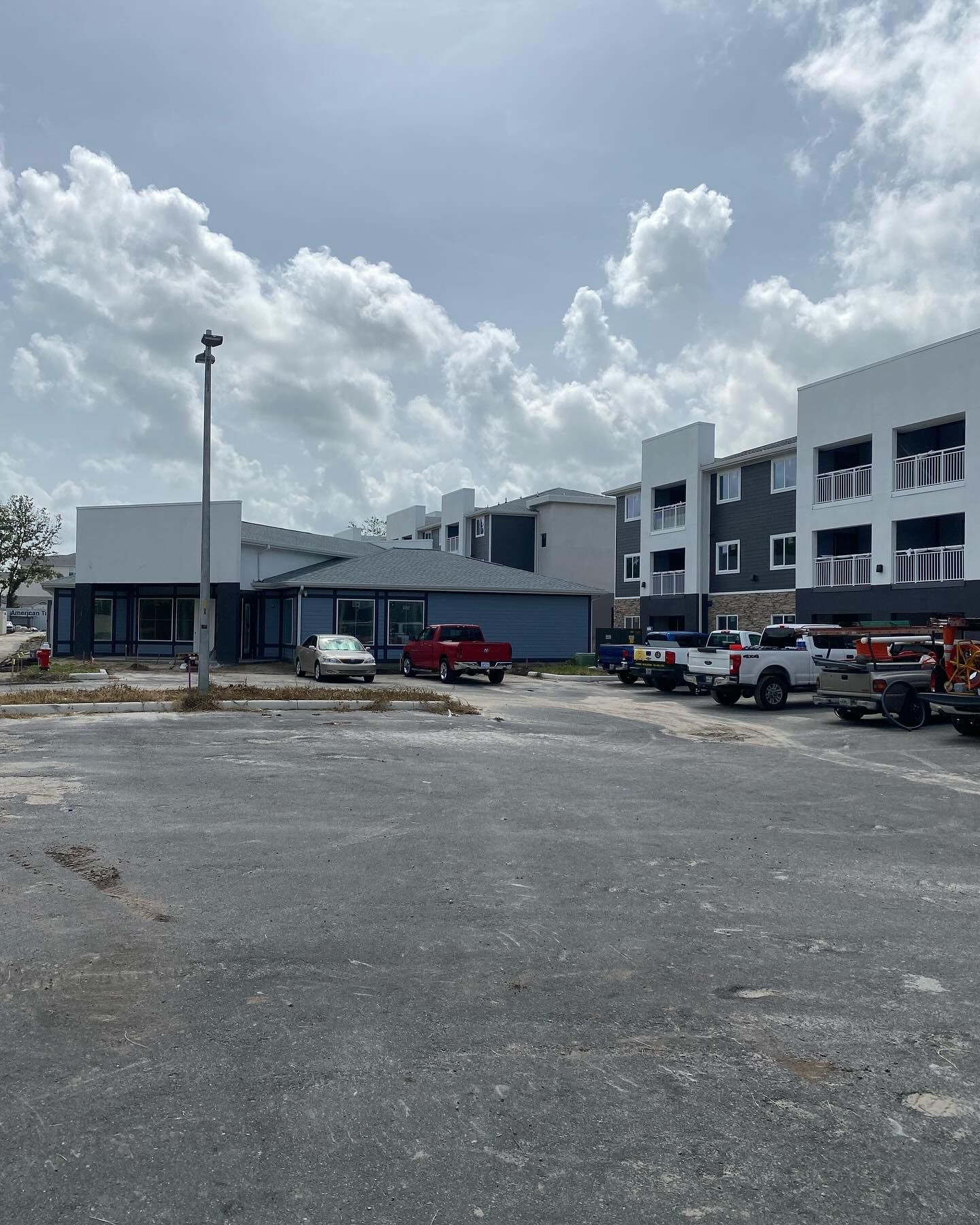 A parking lot with new buildings in the background. Cars and trucks are present. Overcast day.