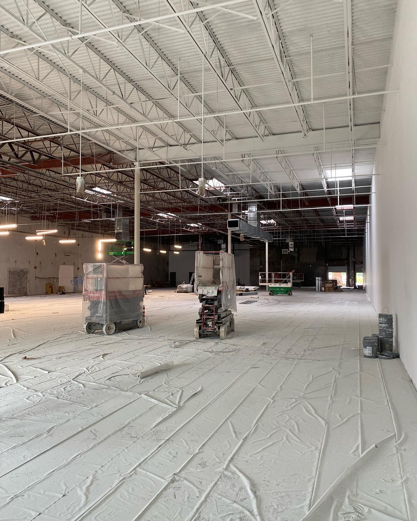 Empty commercial interior under construction with gray flooring and white ceiling.