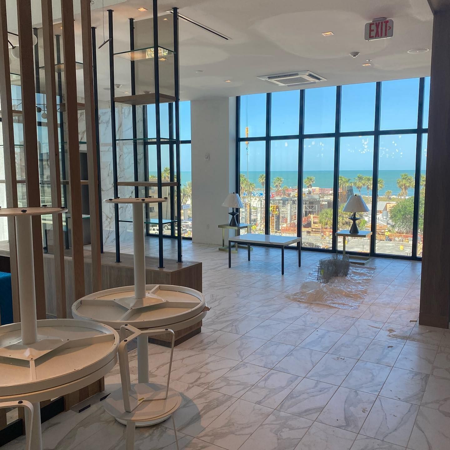 Interior view with tables and ocean view through large windows.