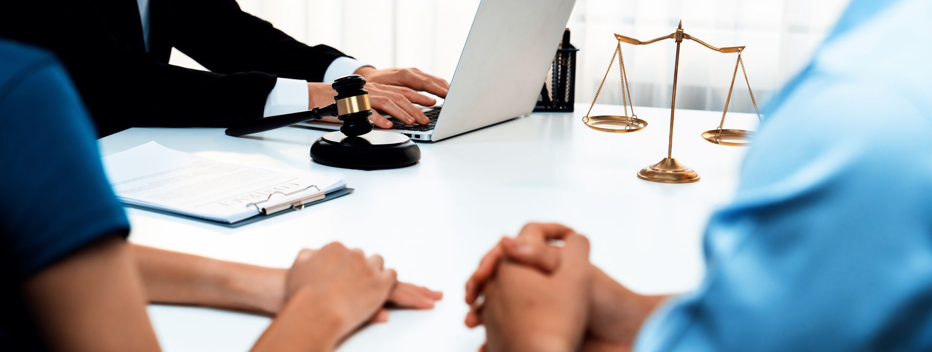 A couple assisted by a lawyer, with computer, gavel, and papers during a divorce mediation process.