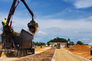 A crane is loading dirt into a dump truck at a construction site.