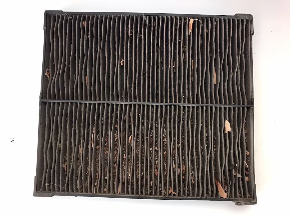 A Dirty Air Filter Is Sitting On A White Surface — Mudgeeraba Auto Electrical & Mechanical In Mudgeeraba, QLD