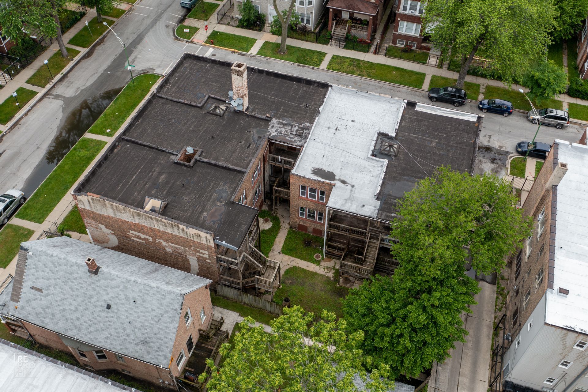Aerial view of old brick buildings with flat roofs and a small courtyard in an urban area.