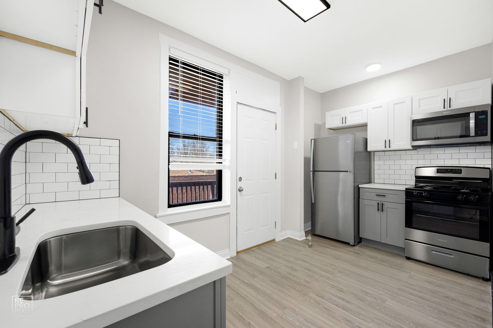 Kitchen with white cabinets, stainless steel appliances, and a window.