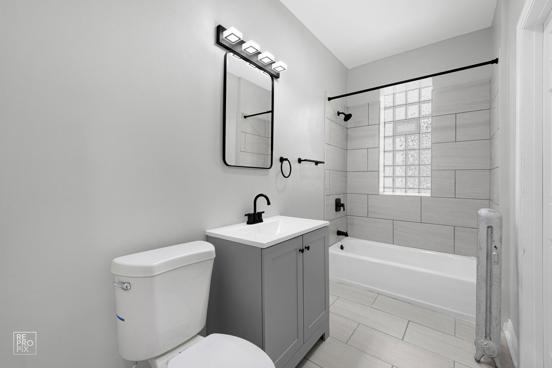 Bathroom with gray vanity, toilet, and tiled shower/bath.