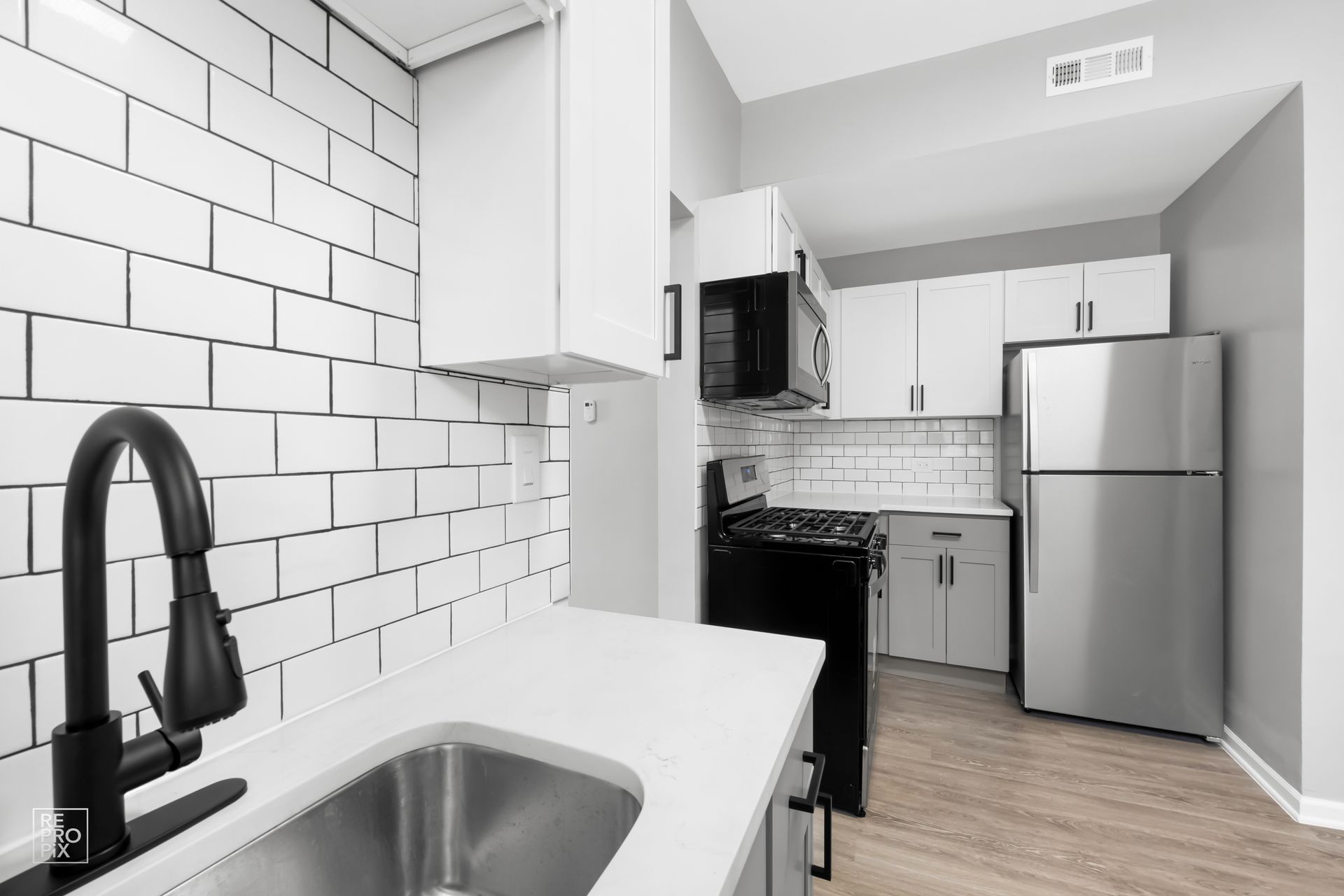 Modern kitchen with white countertops, subway tile backsplash, and stainless steel appliances.