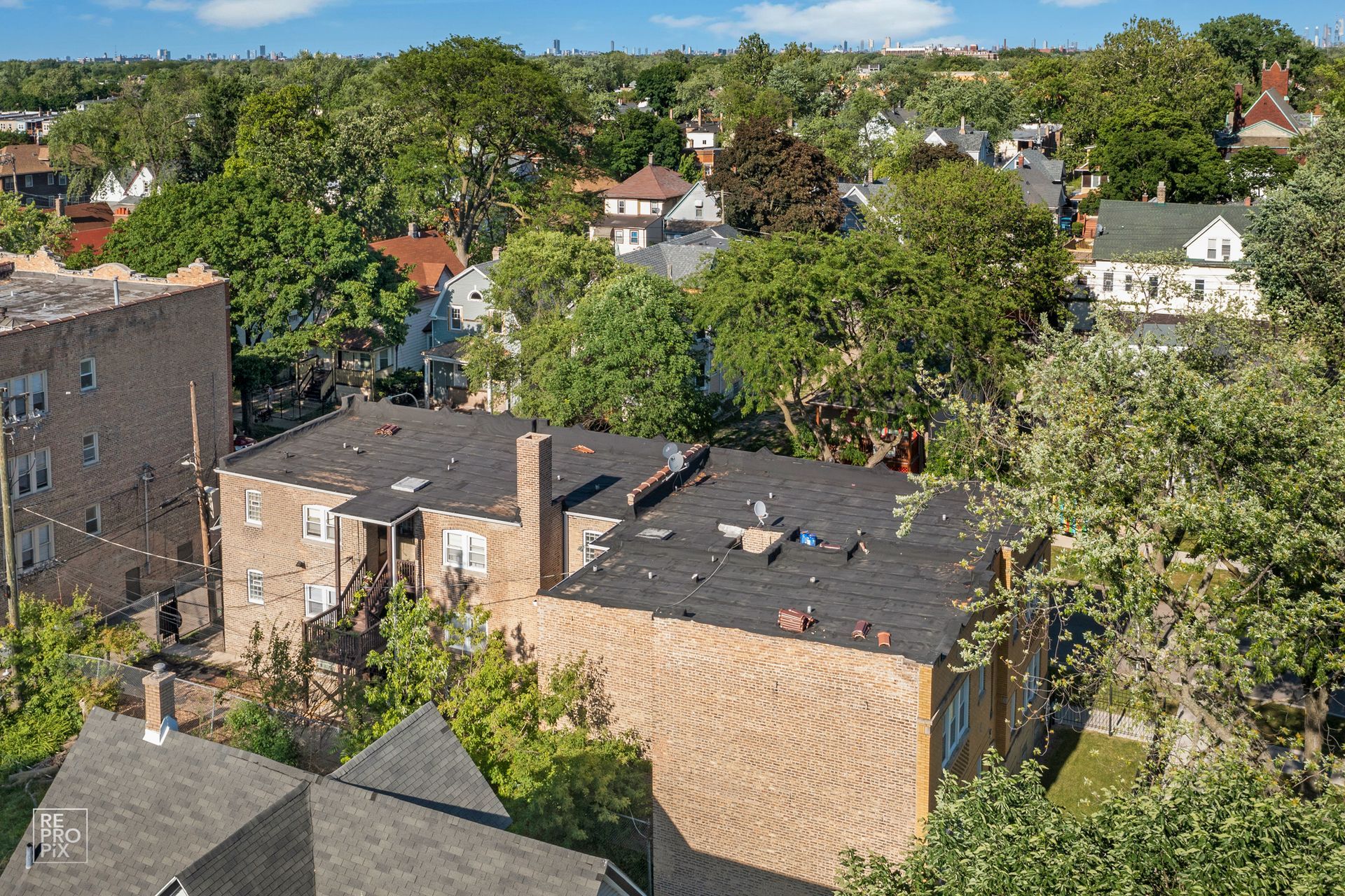 Buildings surrounded by trees under a blue sky, an aerial view of a residential neighborhood.