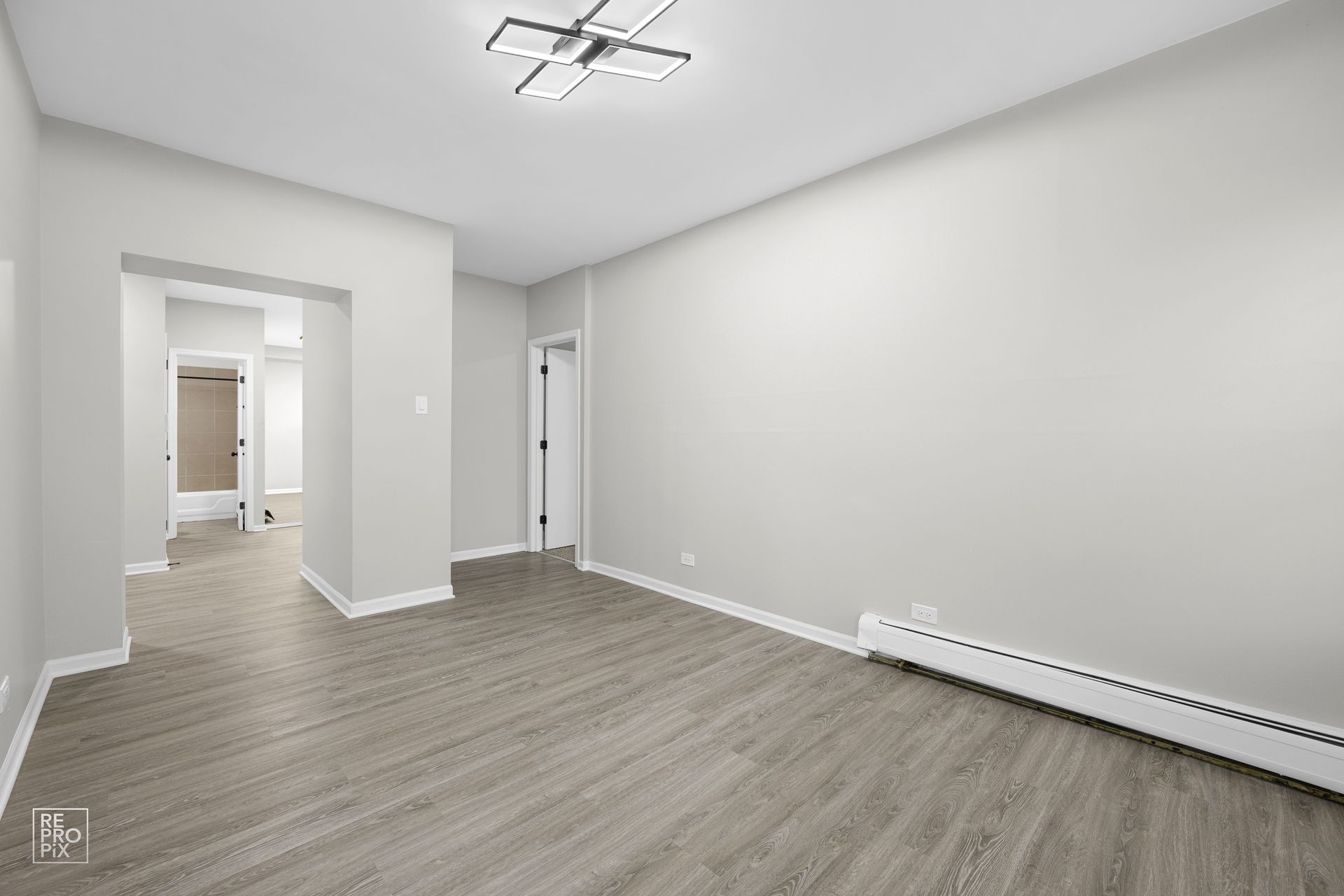 Empty room with gray walls, wood-look flooring, and a white baseboard heater.