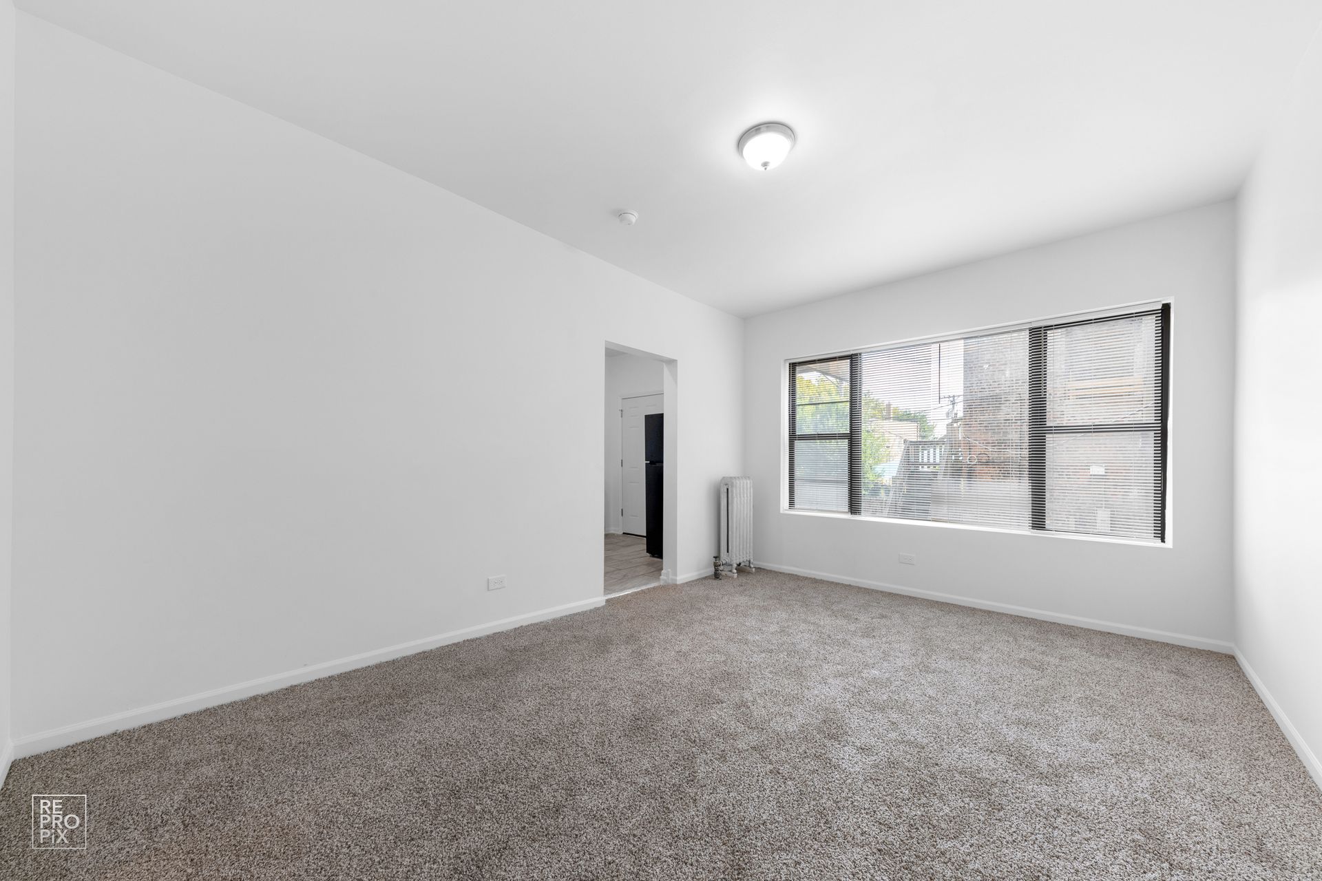 Empty room with gray carpet, white walls, and a window with blinds.