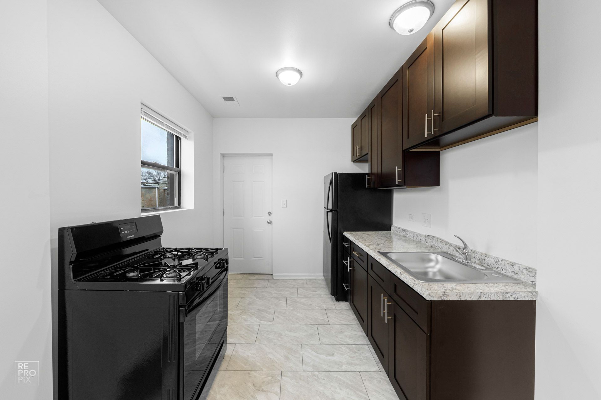 Black kitchen with black appliances, dark cabinets, and light countertop.