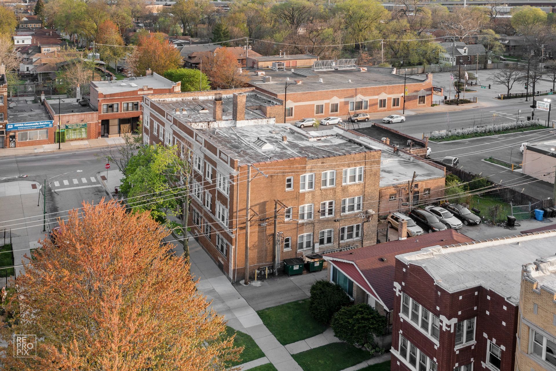 Aerial view of brick apartment buildings and surrounding urban neighborhood with trees and parked cars.