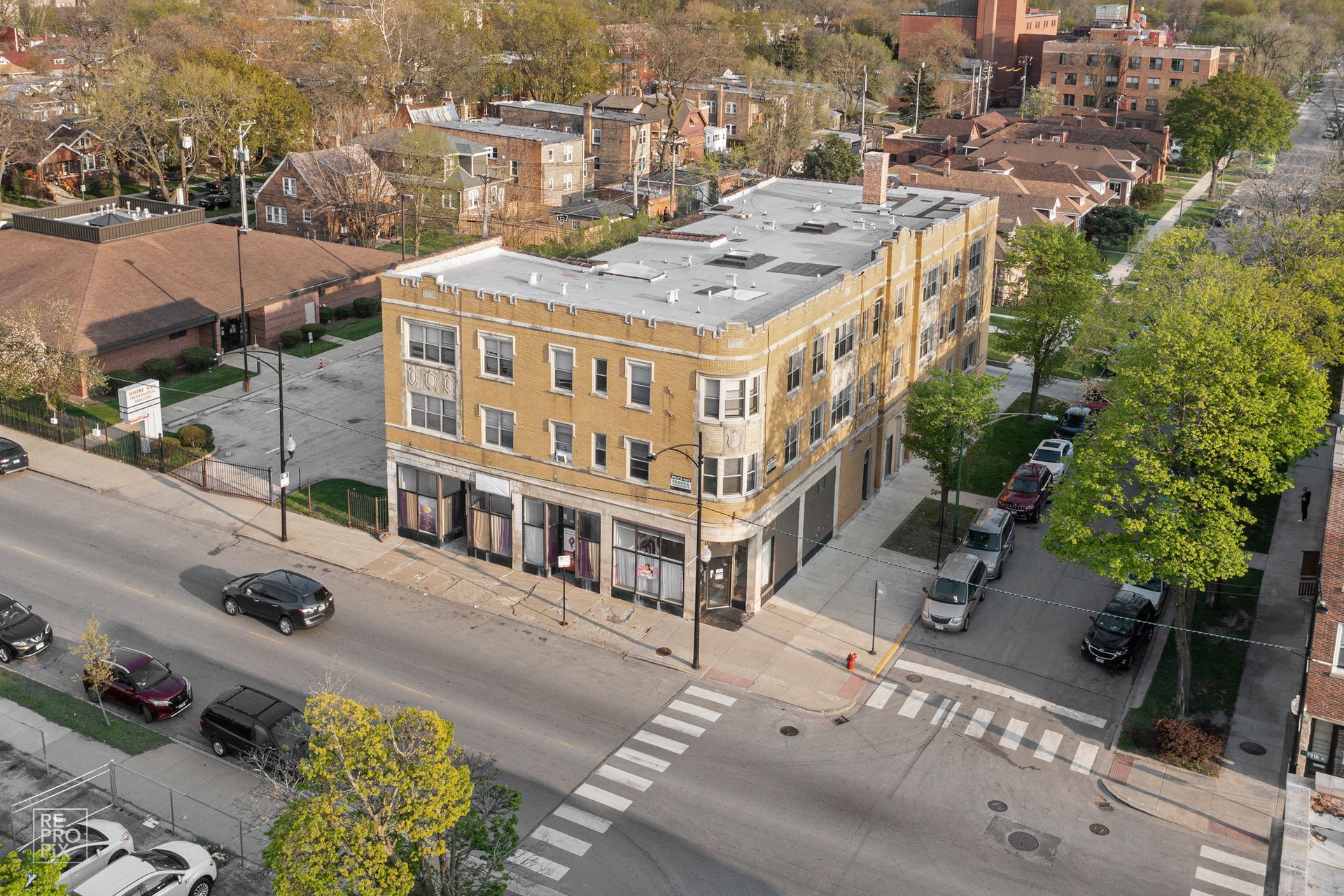 Aerial view of a three-story beige building with shops on the first floor, street and cars.