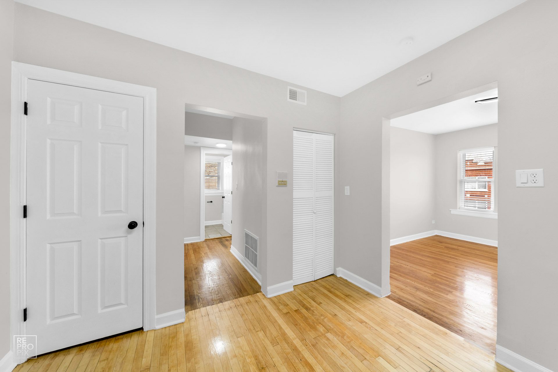 Interior hallway with light gray walls, wooden floors, and white doors leading to rooms.