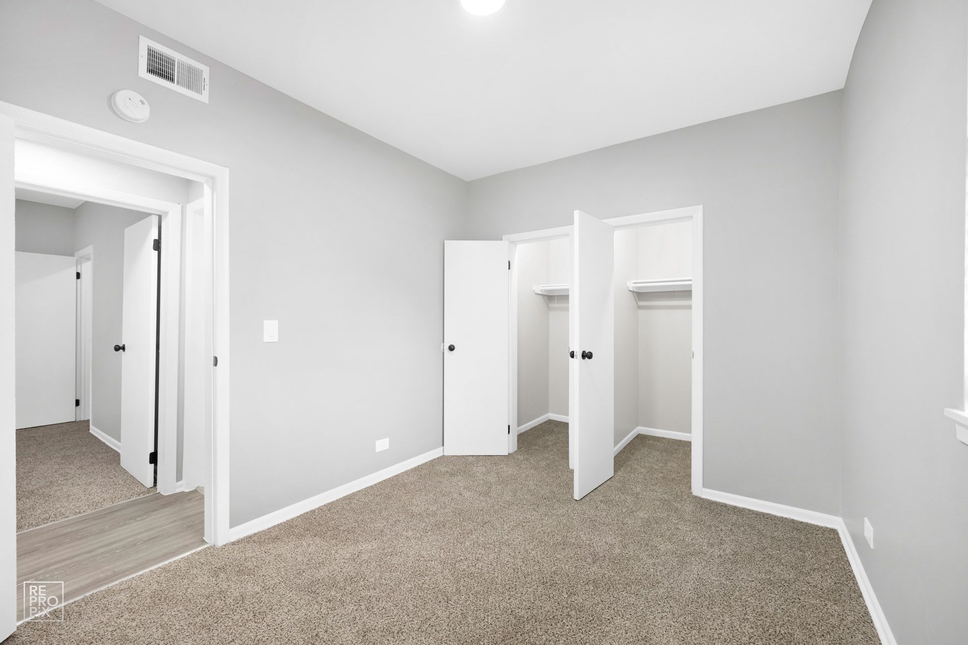 Empty bedroom with gray walls, carpet, and a closet with two doors.