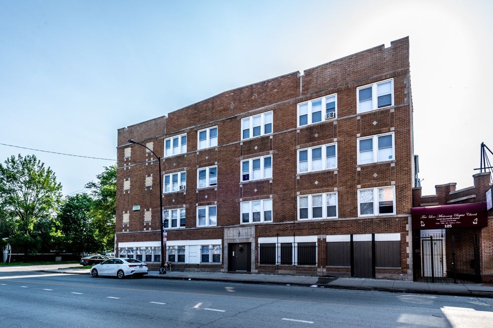 Brick apartment building on a city street, blue sky.