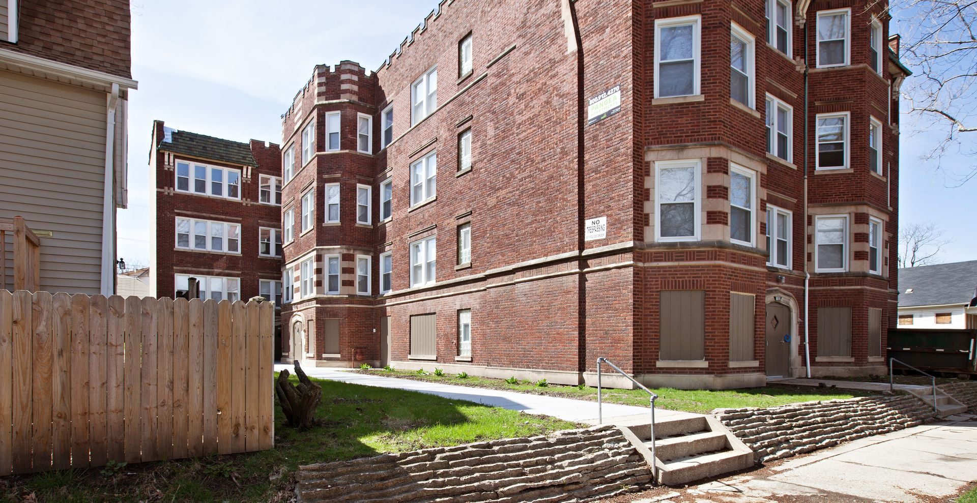 Brick apartment buildings with a grassy area and sidewalk.