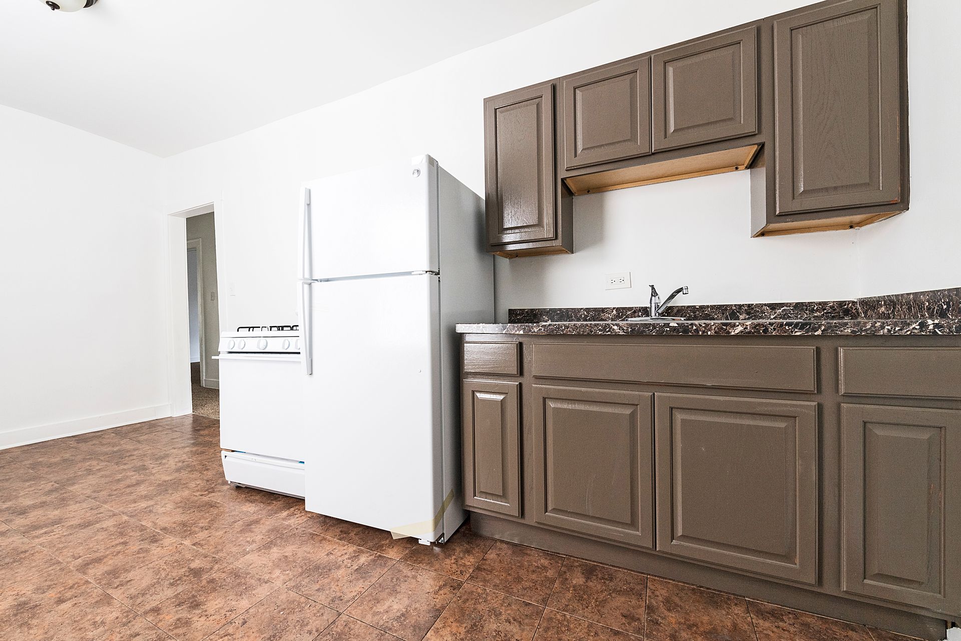 Kitchen with brown cabinets, white appliances, and speckled countertop.