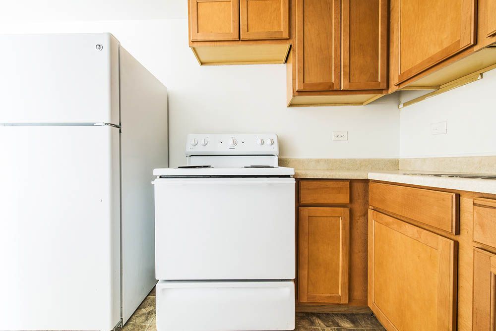 Kitchen with white refrigerator, stove, and light wood cabinets.