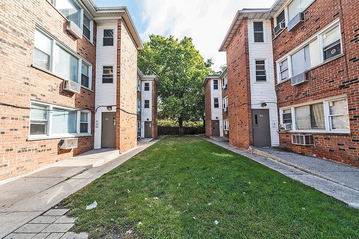 Apartment complex courtyard with green grass, walkways, and brick buildings.