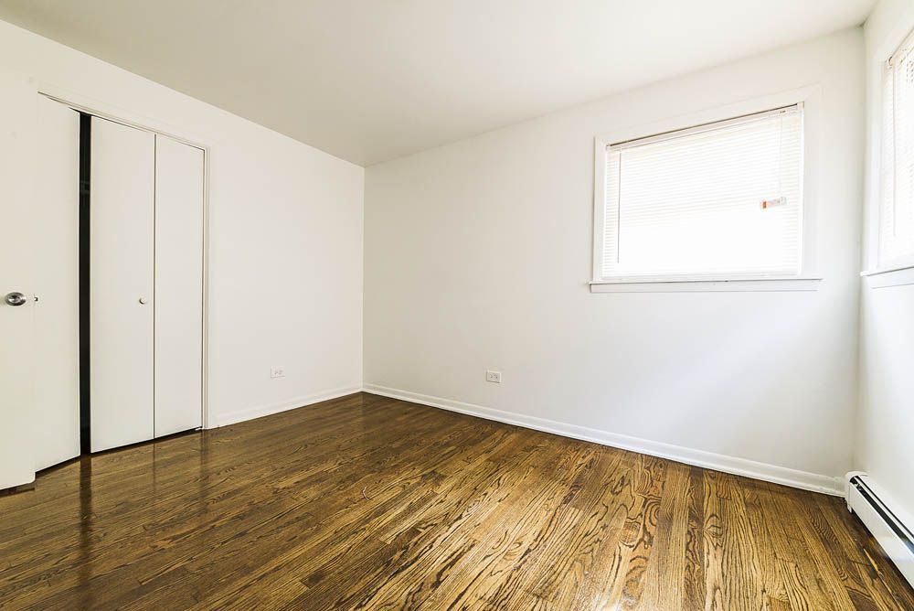 Empty room with hardwood floor, white walls, closet, and a window with blinds.