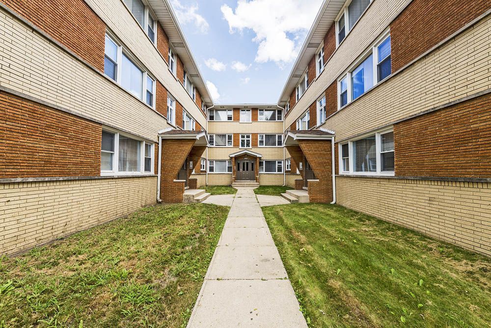 Courtyard apartment building with brick exterior and central walkway.