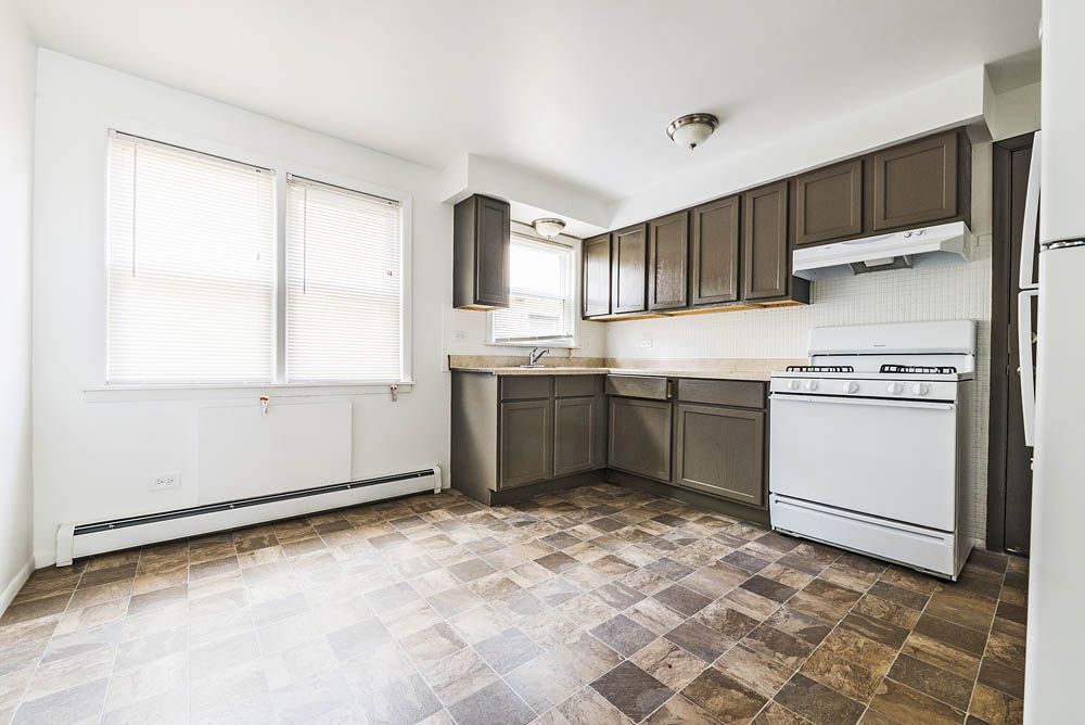 Kitchen with brown cabinets, white appliances, and checkered flooring.