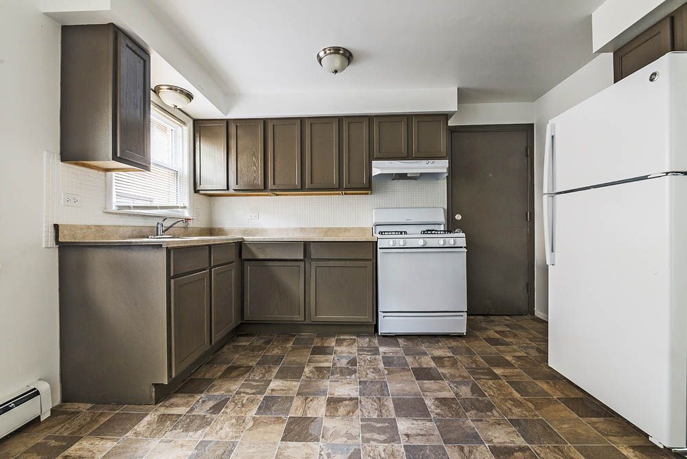 Kitchen with brown cabinets, white appliances, and patterned floor.
