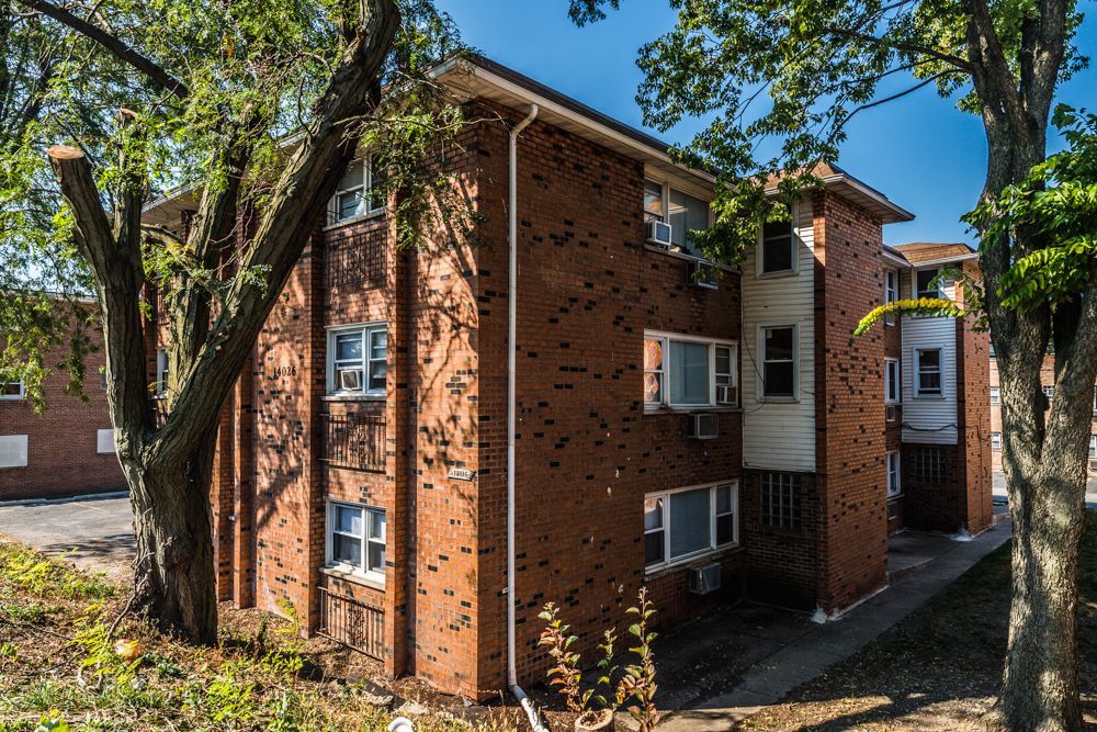 Brick apartment building exterior with white trim and air conditioners.