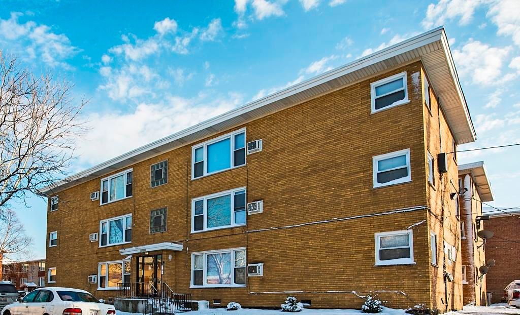 Apartment building with yellow brick facade, blue sky, and snow.