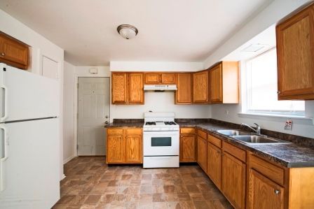 Kitchen with brown cabinets, white appliances, and a window.