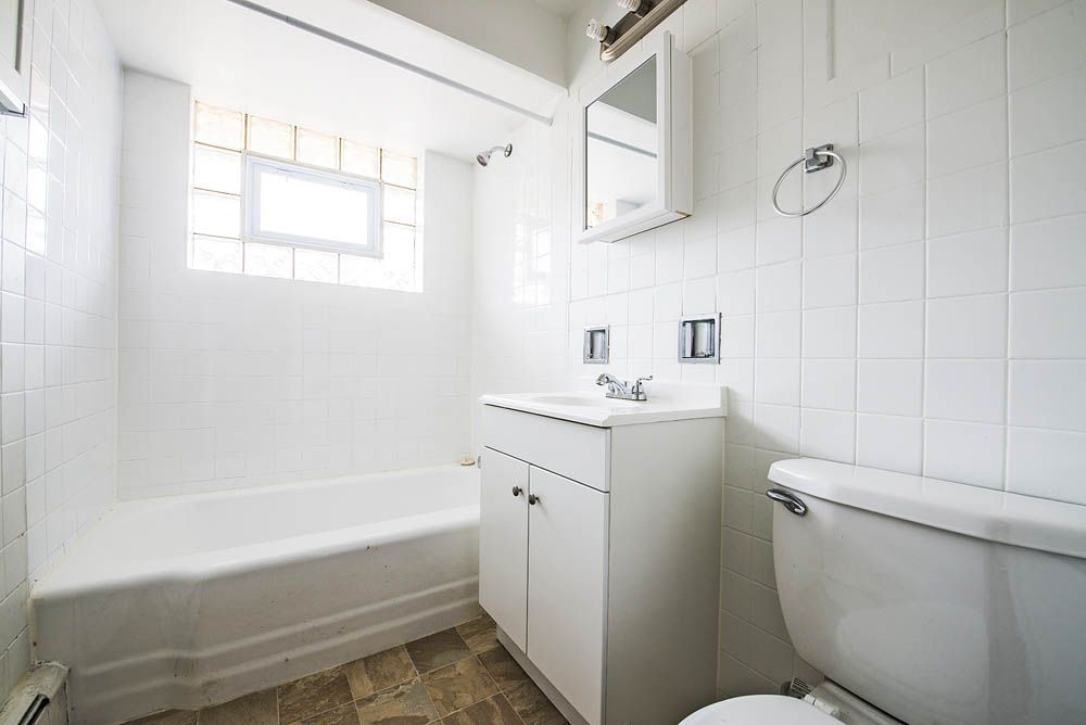 White bathroom with a bathtub, toilet, sink, and window.
