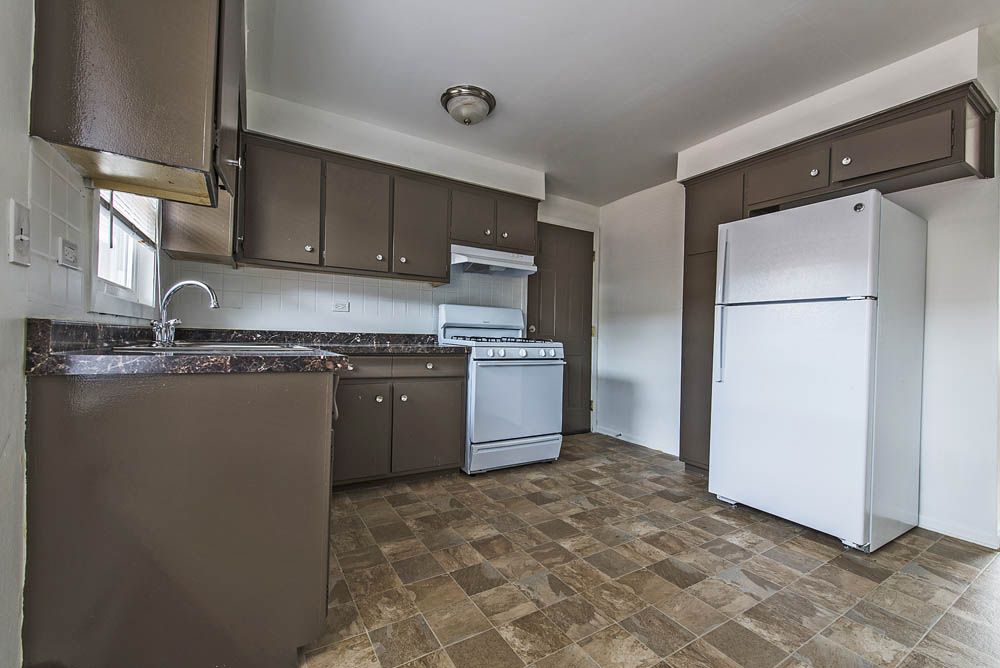 Kitchen with brown cabinets, white appliances, and patterned floor.