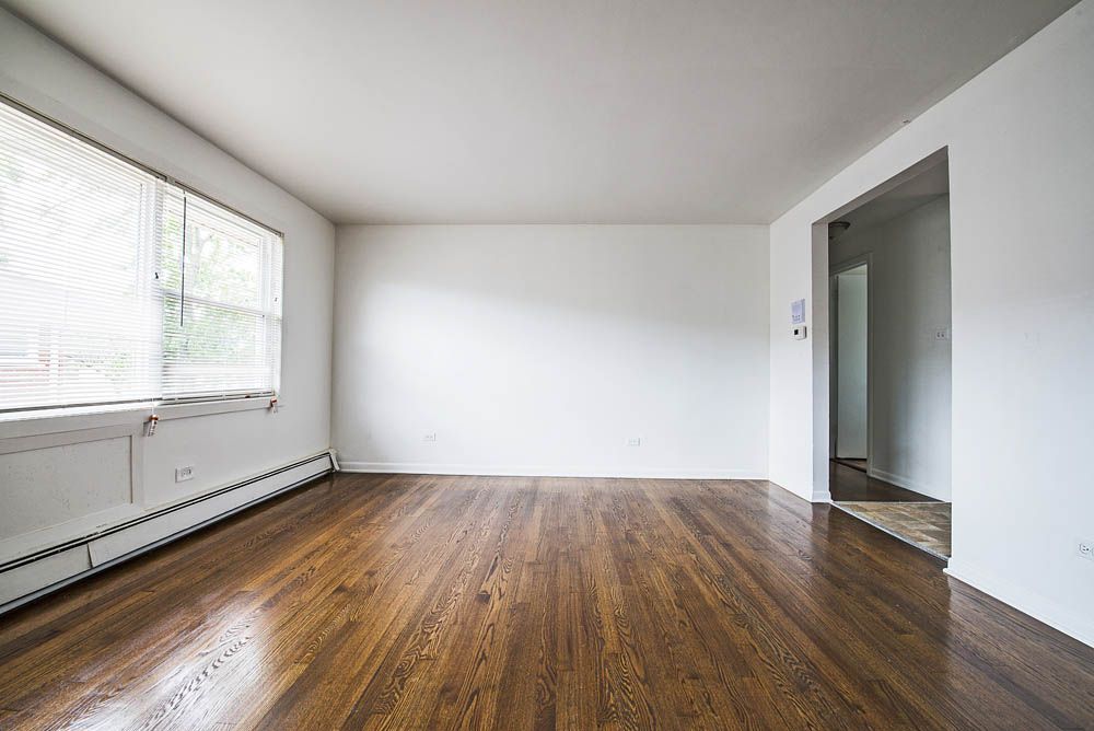 Empty room with wood floors, white walls, and a window.