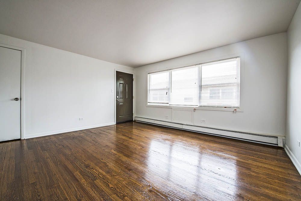 Empty room with hardwood floors, a door, and a window.