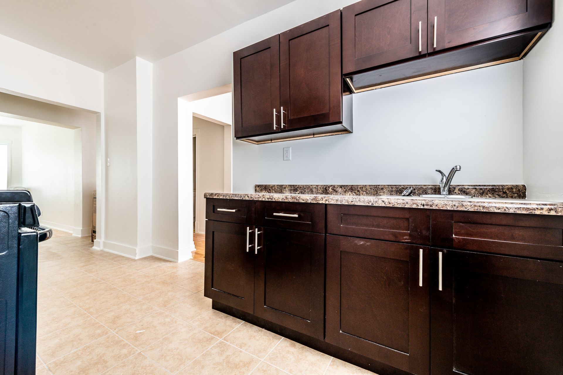 Dark-stained kitchen cabinets with marble countertop and a sink.