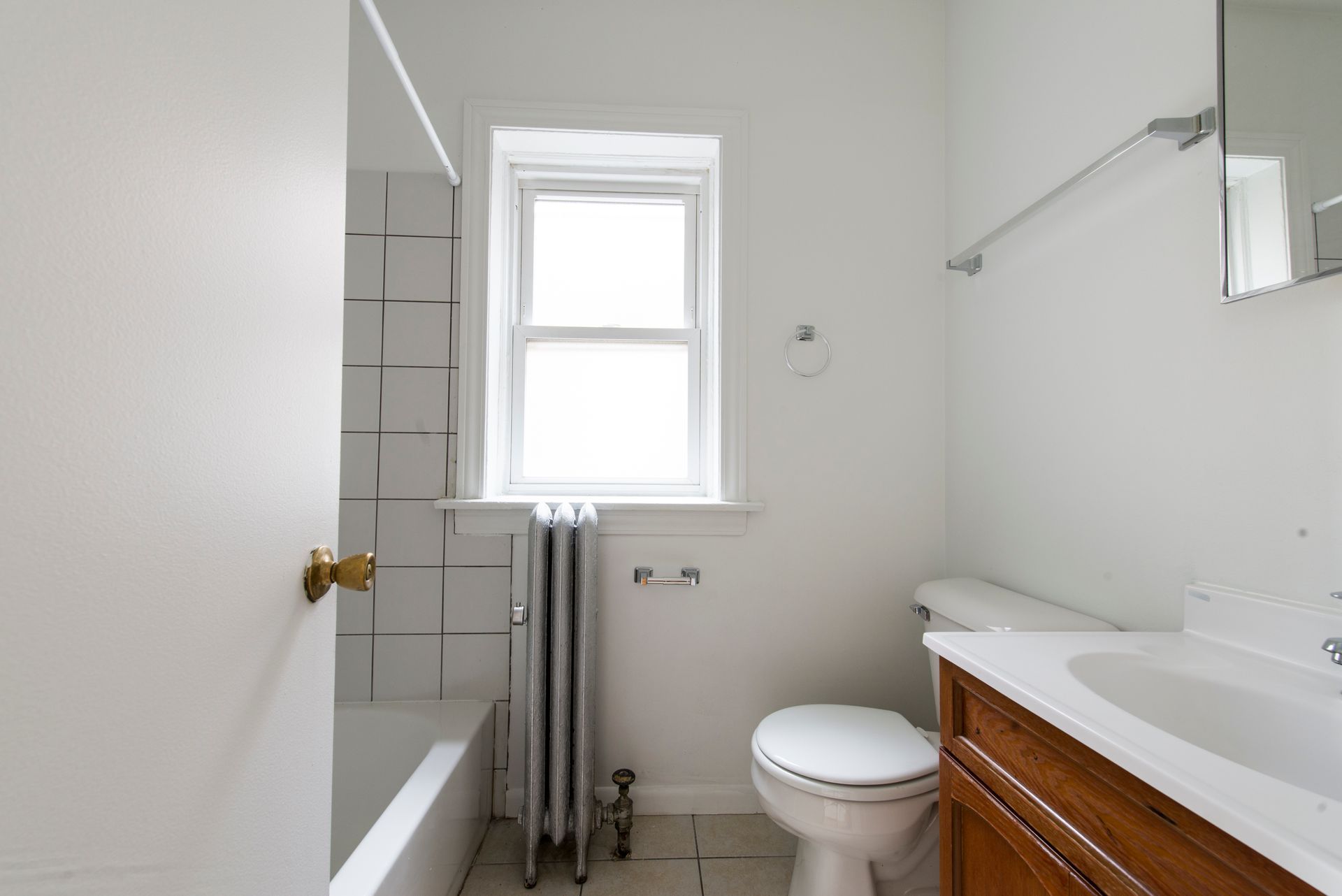 Bathroom with white walls, window, toilet, sink, and bathtub with tile surround.