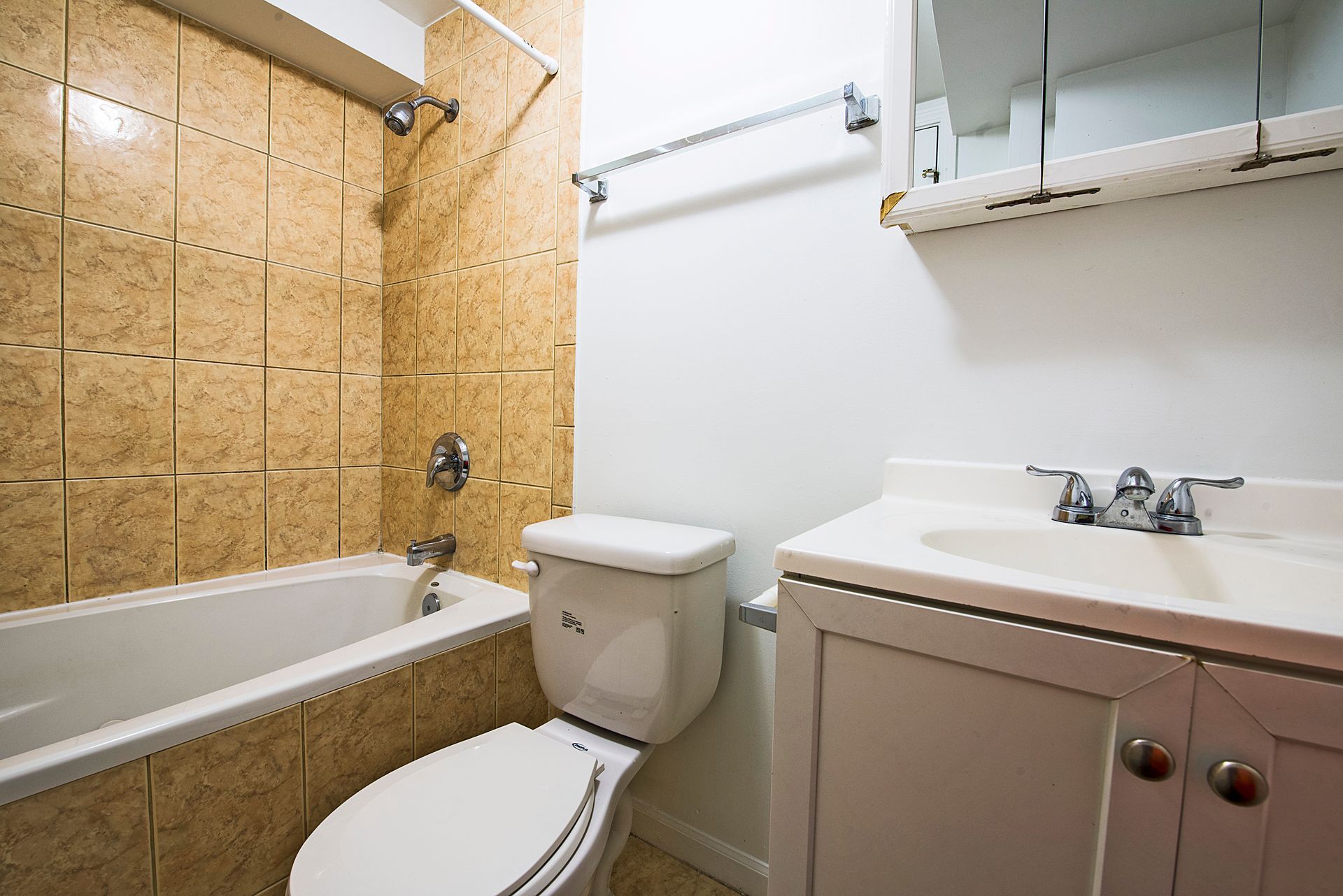 Bathroom with white fixtures, beige tiled wall, and a vanity.