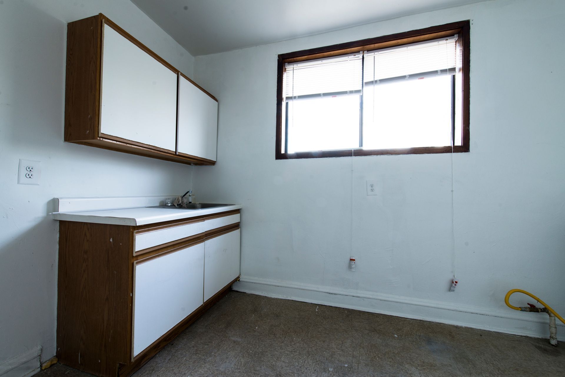 Small room with white cabinets and sink, window, and brown trim.