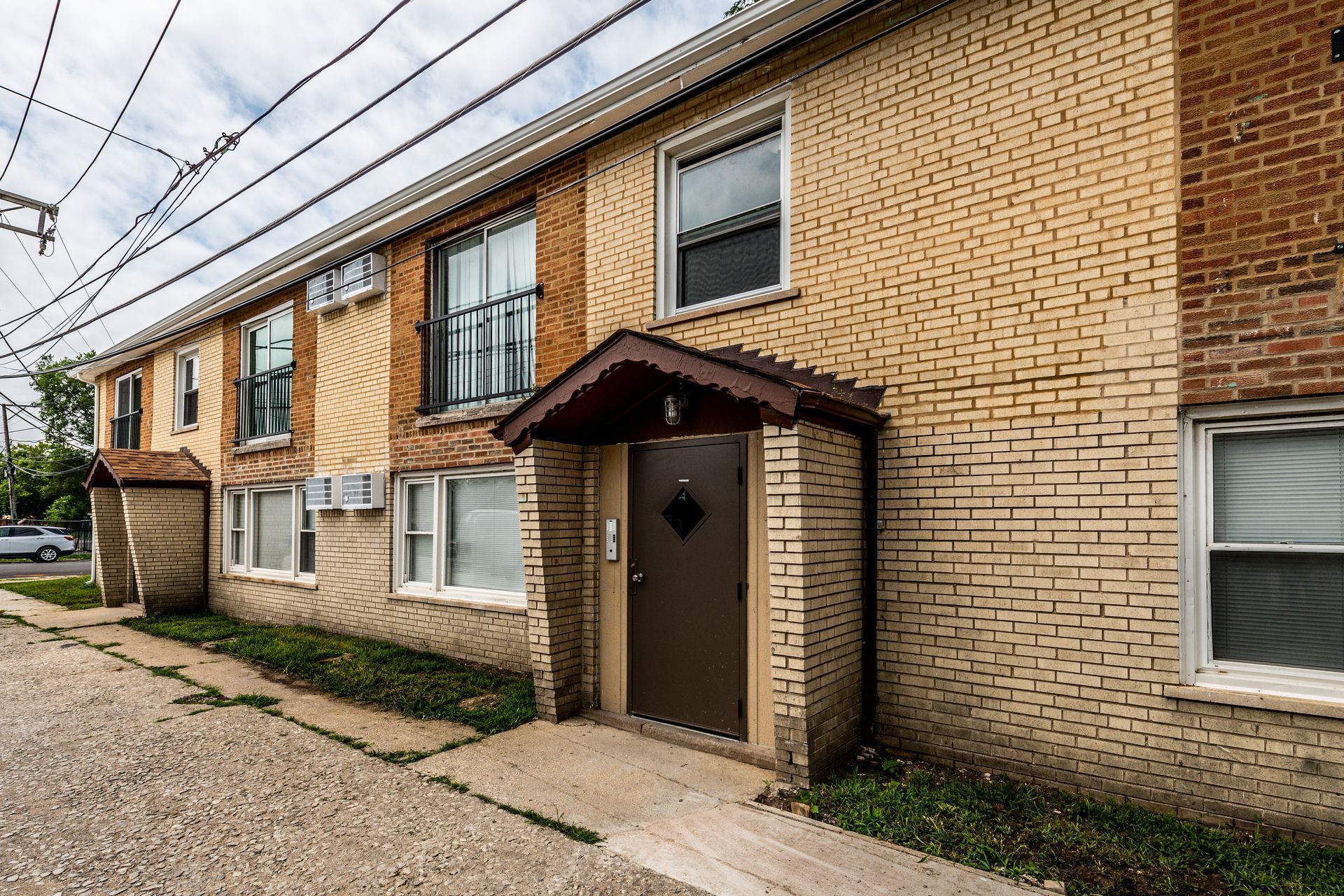 Two-story brick apartment building with brown doors, windows, and overhead power lines.