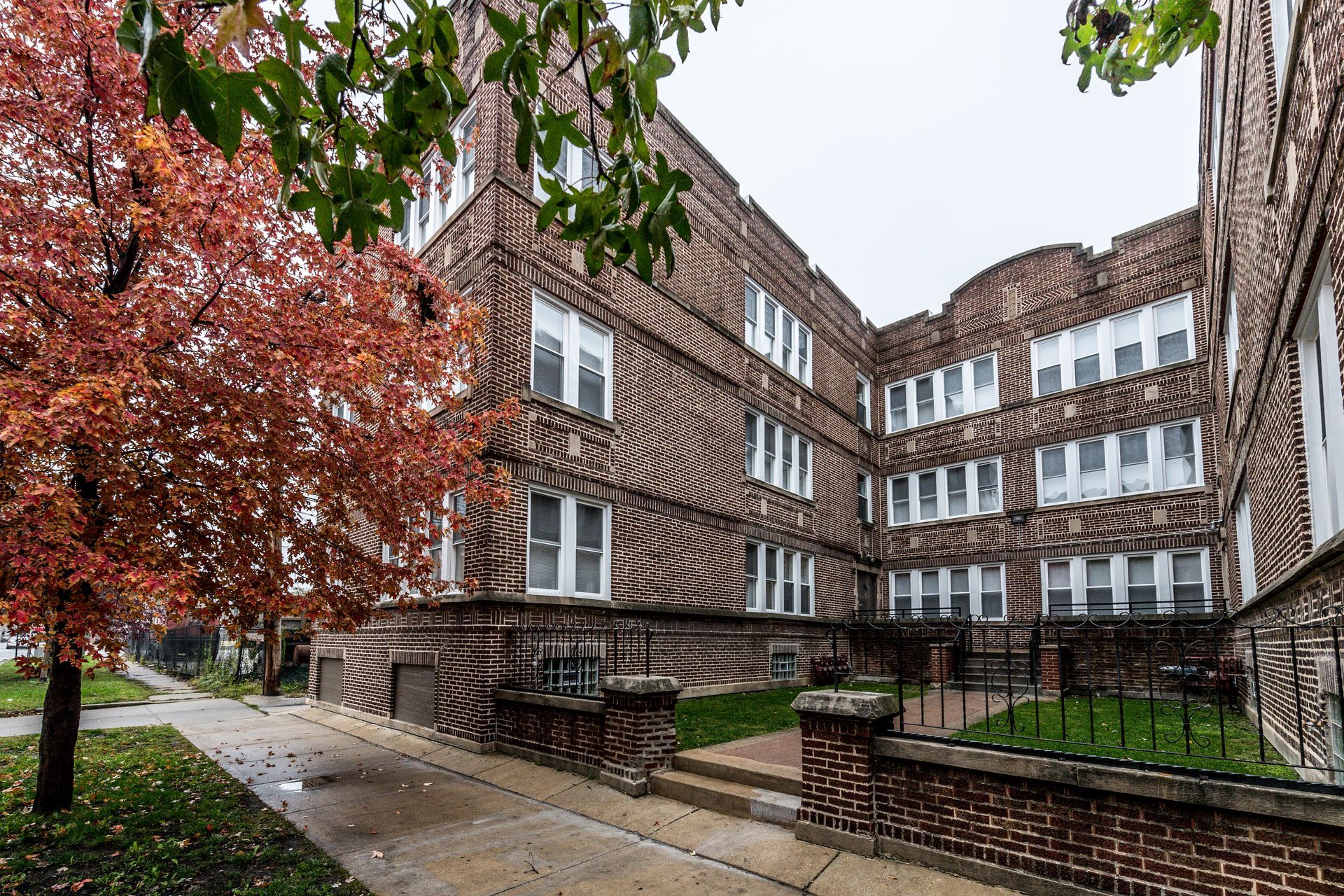 Brick apartment building with autumn tree on a cloudy day.