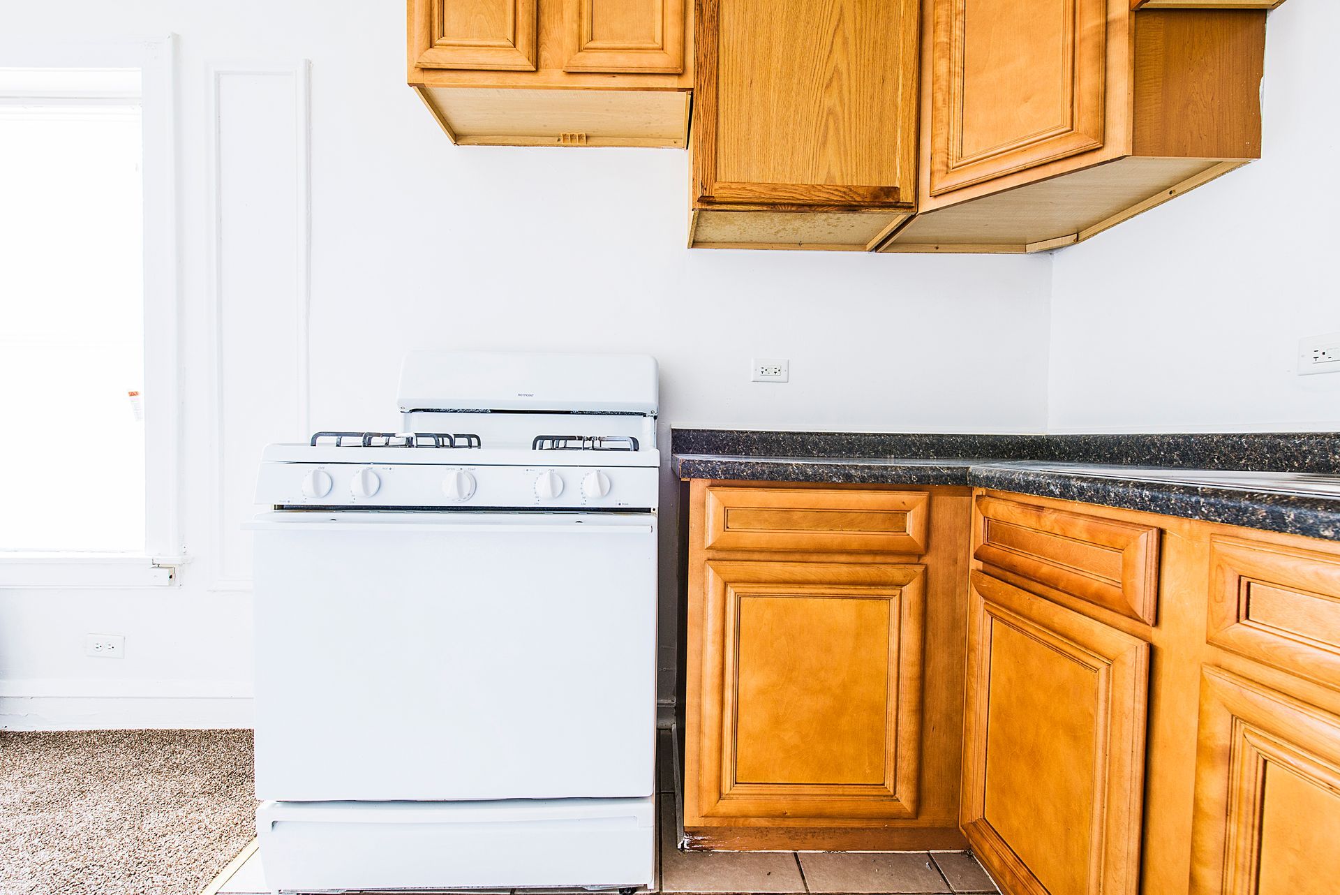Kitchen with white stove, wood cabinets, and dark countertop.